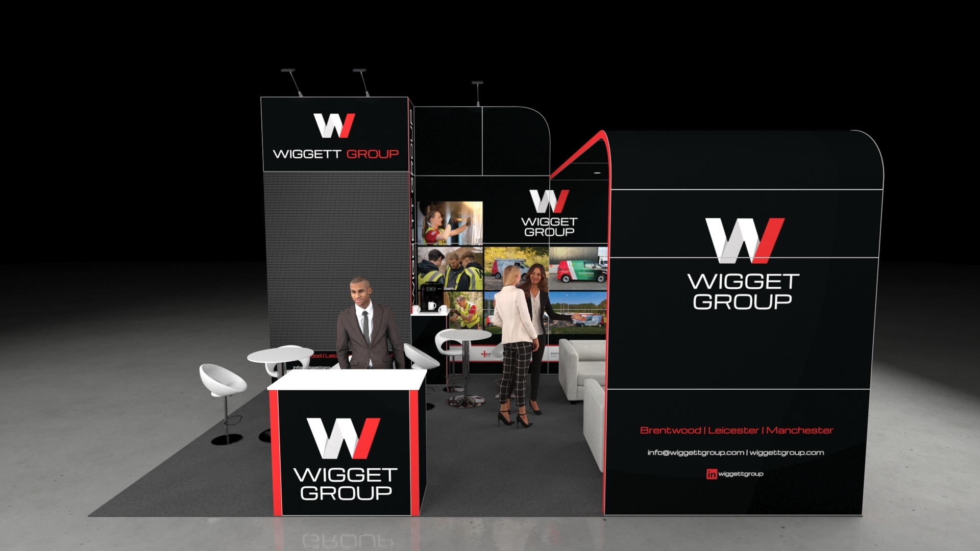 Maryport3 3D render of a modern trade show booth design. The stand features a tall, black and red graphic wall on the left, a semi-enclosed lounge area with grey sofas on the right, and high-top white tables with stylized stools for networking in the centre.